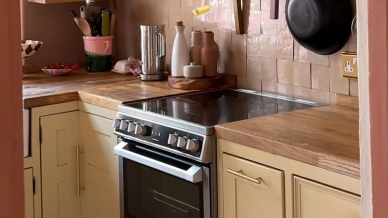 Small, mauve kitchen with butter yellow cabinets