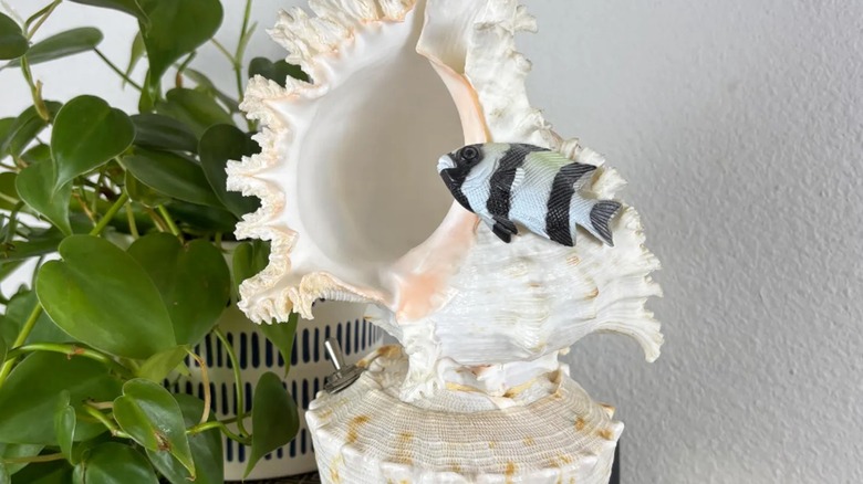 A vintage white seashell lamp with fish on it.