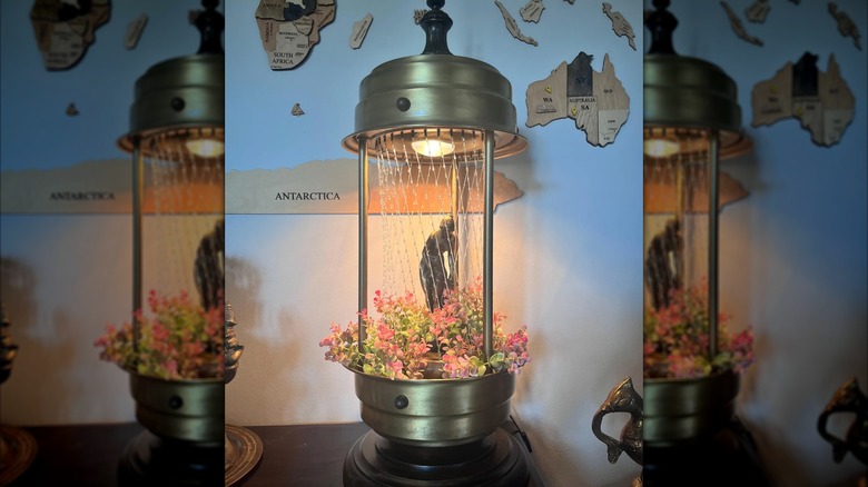 A rain oil lamp with flowers on table.