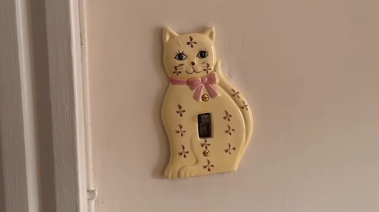 A vintage cat light switch cover on wall.