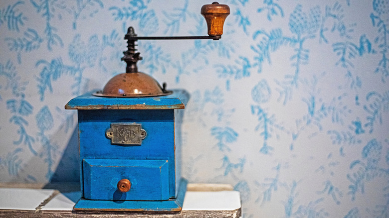 An old-school blue coffee grinder on a kitchen worktop