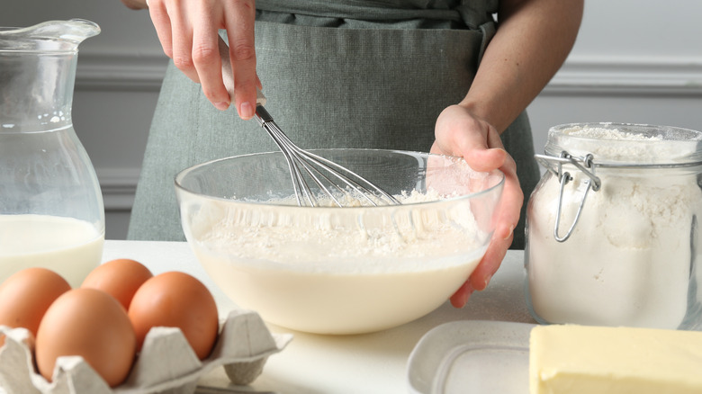 A hand holding a stainless steel whisk