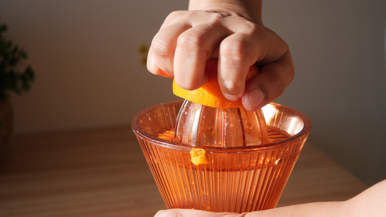 Hands using an old-school manual fruit juicer