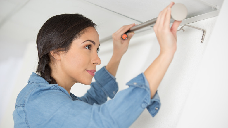 woman installing rod in closet