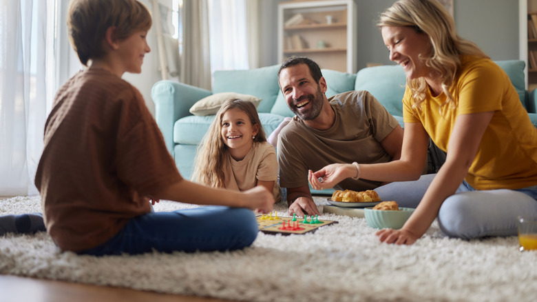 A happy family sitting on carpet and playing Ludo