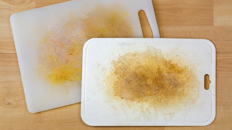 Two old, scratched, and stained white plastic cutting boards on a butcherblock countertop