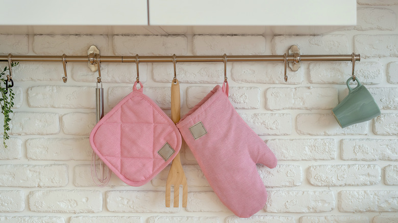Pink oven mitt and pot holder hanging on rack in the kitchen
