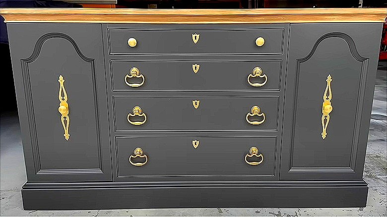 A gray sideboard with a wood top and gold hardware.