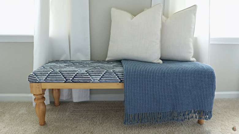 A close up on a gold bench with an upholstered seat.