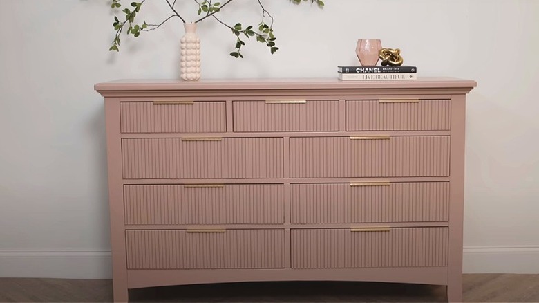A tan pole wrap dresser with gold pulls.
