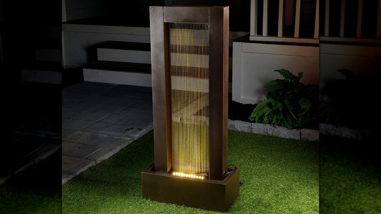 A metal rainfall fountain in a dimly lit garden