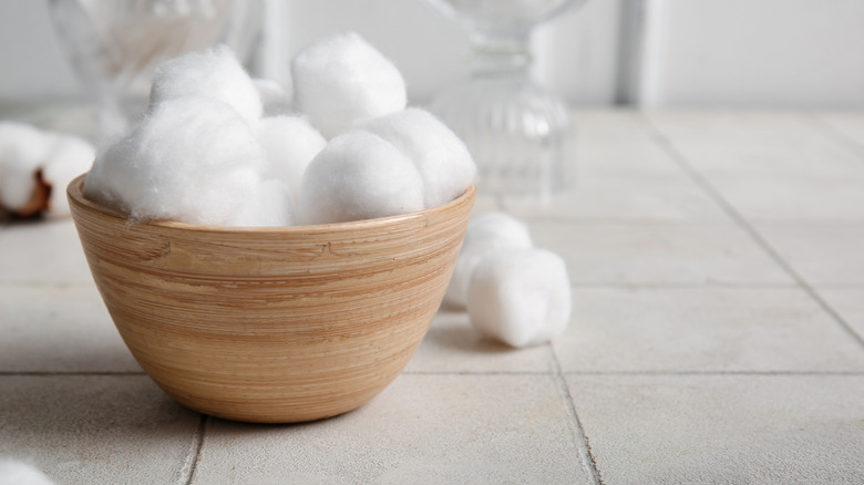 Bowl filled with cotton balls on white tile
