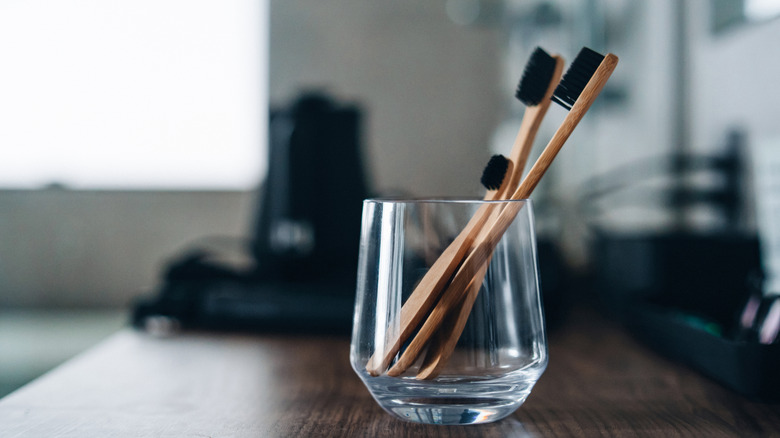 Bamboo toothbrushes in a glass on a table
