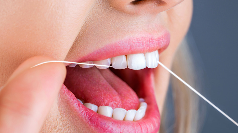 Woman using dental floss between her teeth