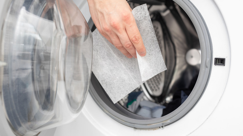 Hand putting a dryer sheet in the machine