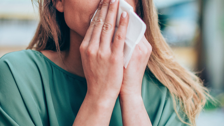Woman blowing her nose with a white tissue
