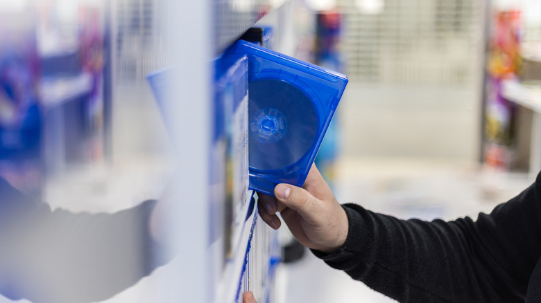 Close-up of a hand pulling out a DVD from a shelf