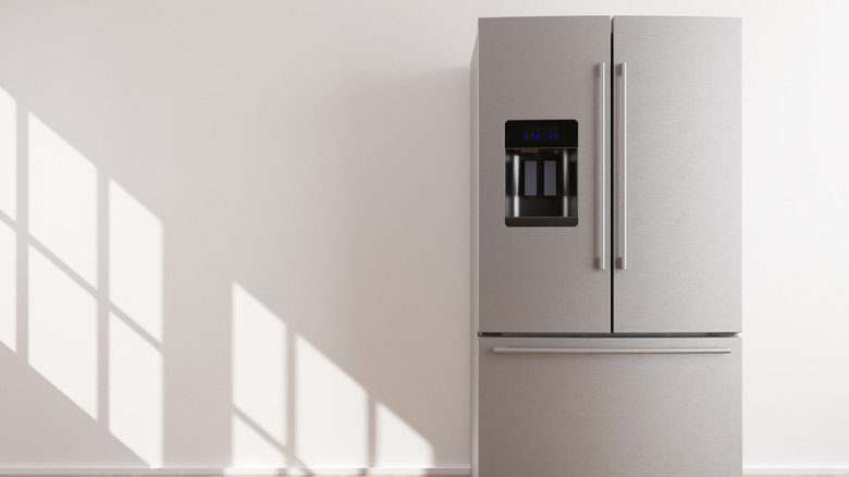 Stainless steel refrigerator against a white wall