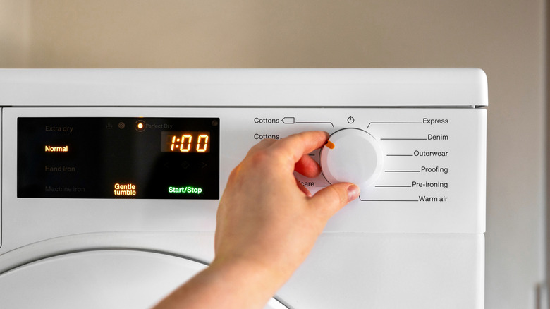 Hand adjusting settings on dryer