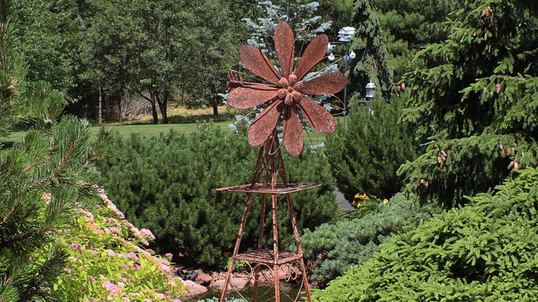 A rusty-looking windmill made of metal in a garden