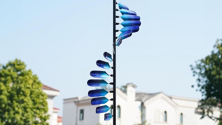 A windmill spinner, in shades of blue, with houses in the background