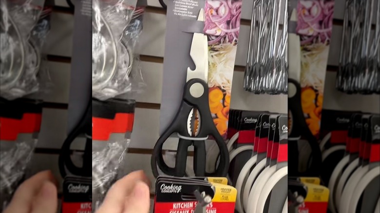A pair of kitchen shears hangs on a display wall in a Dollar Tree store.