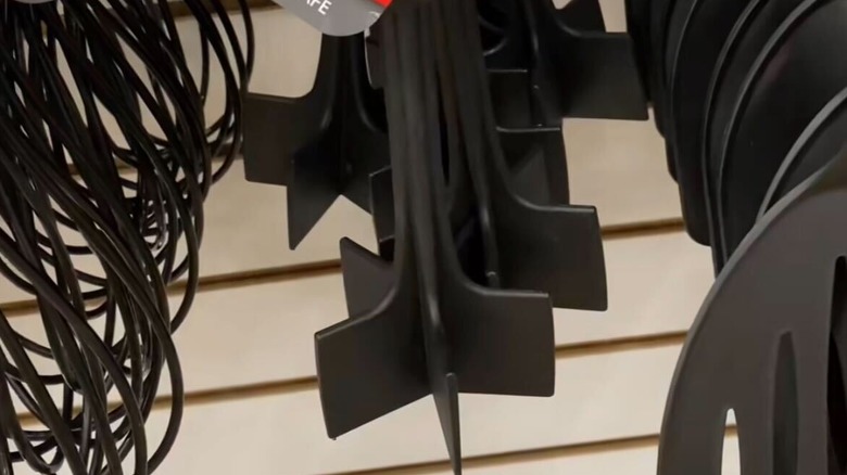 A black plastic meat chopper from Dollar Tree hangs on a display wall next to whisks and turners.