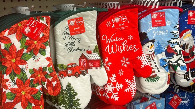 A row of holiday-themed oven mitts hanging on a display wall at Dollar Tree.