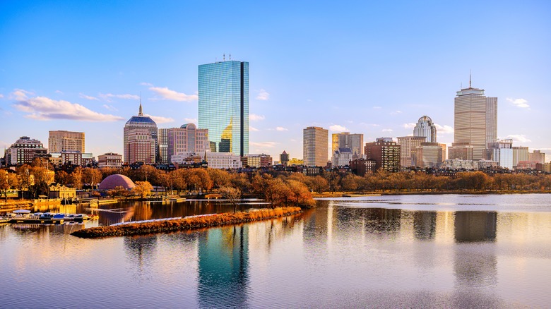 Boston City Skyline over the Charles River in Massachusetts, USA. A tranquil riverscape of Back Bay with golden illuminated wintery foliage in New England.