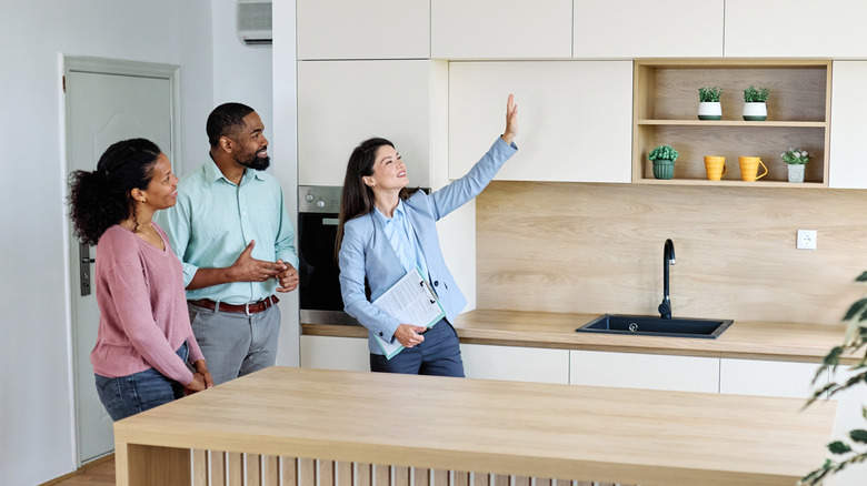 A real estate agent shows a couple a kitchen