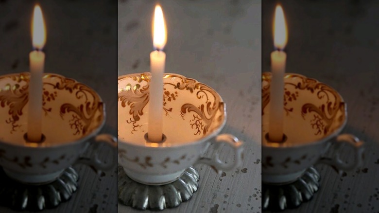 candlestick burning in white teacup
