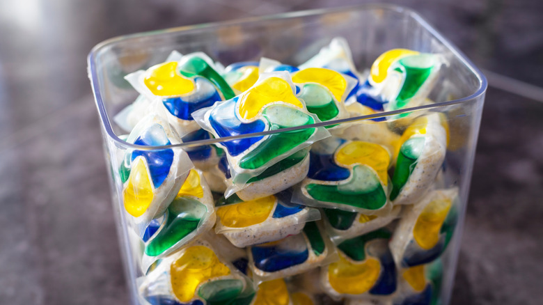 Dishwasher pods in a clear container on kitchen counter.
