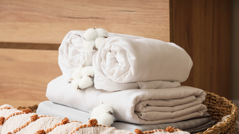 A stack of linens and towels in a wicker basket.