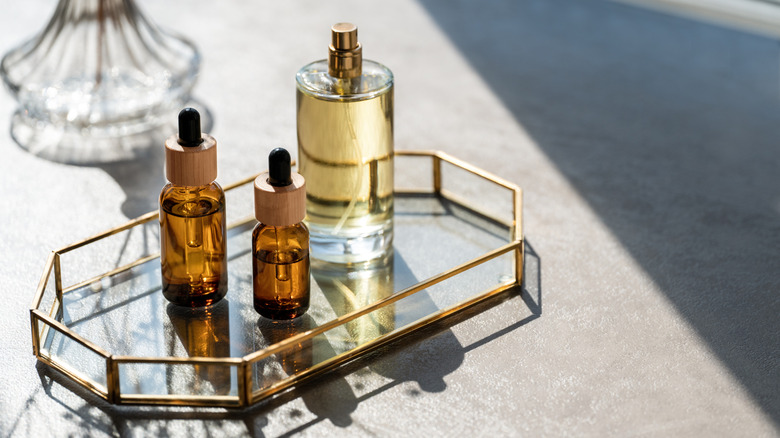 glass and gold tray with perfume and serum drops on top