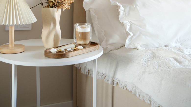 wood tray on bedside table with drink and beauty supplies on it