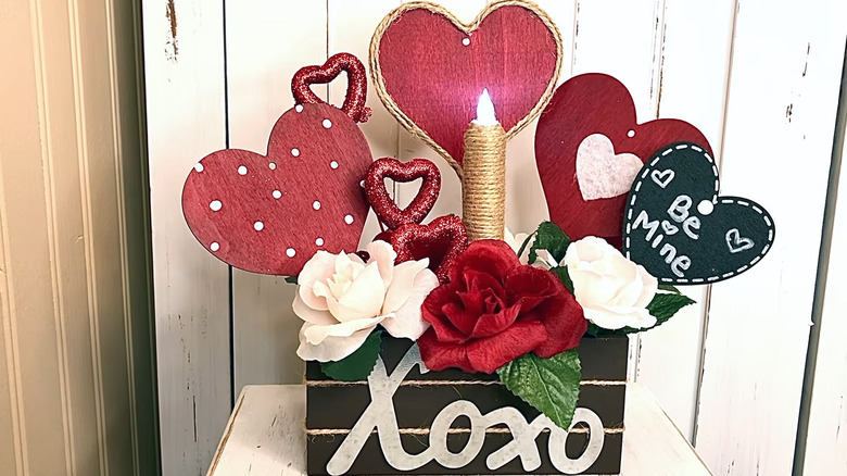 Valentine's centerpiece with various heart-shaped elements and artificial flowers in a Dollar Tree wooden crate
