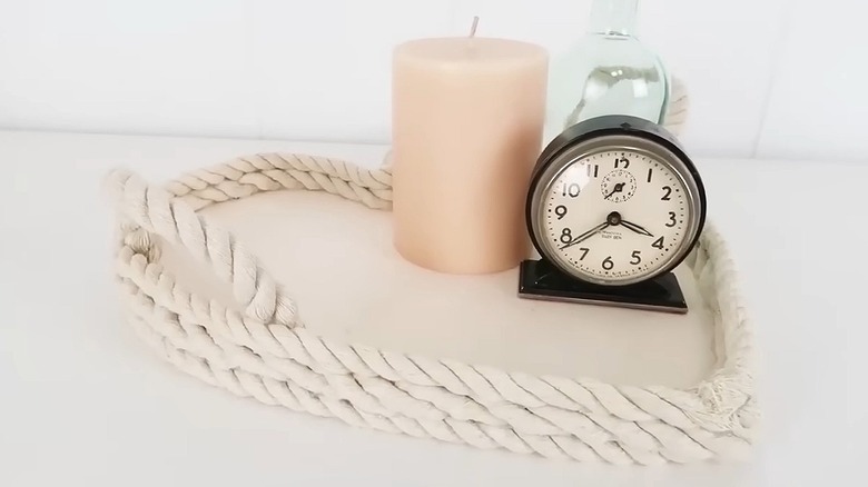 Wooden heart-shaped tray with nautical rope sides styled with a candle and an alarm clock