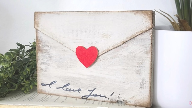 Piece of wood painted to look like an envelope with a heart and "I love you!" written on it