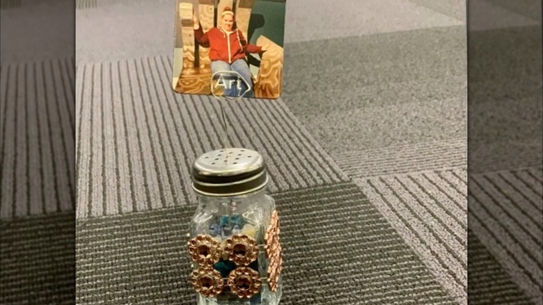 A salt shaker photo holder with gold details and a photo in a wire stand on top.