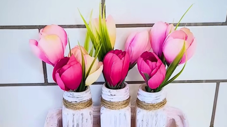 Tulips in salt and pepper shaker vases in front of a white-tiled kitchen backsplash.