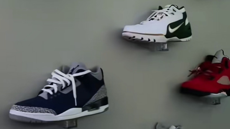 Three shoes balanced on salt and pepper shaker pegs sticking out from a wall.