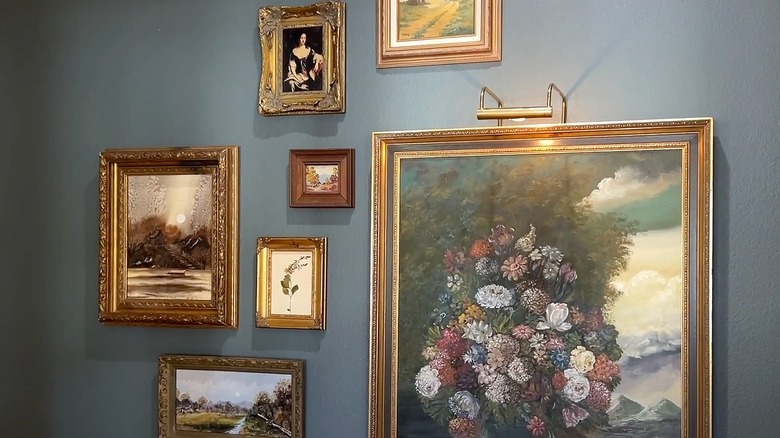 Gold-toned art frames hanging on a dark entryway wall