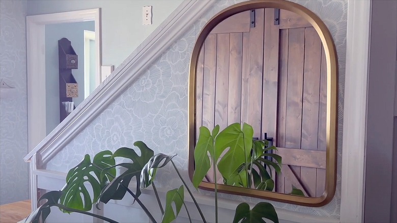 An entryway with a large mirror hung above a plant