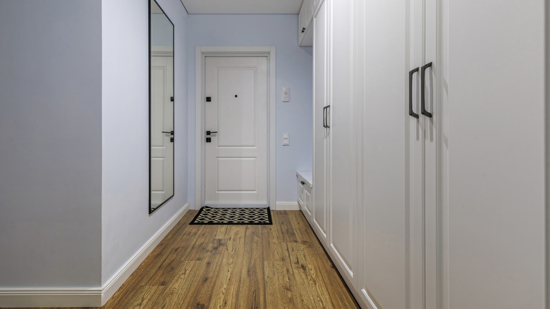 Narrow entryway with pale blue walls and white cabinets