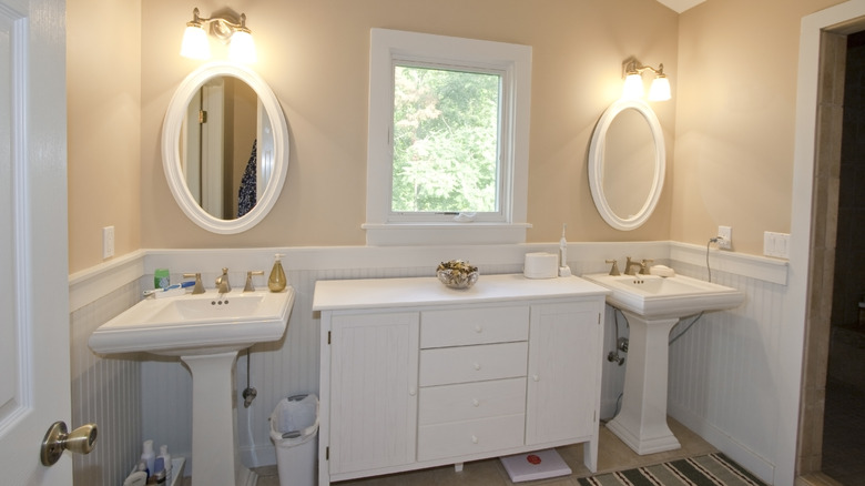 Two pedestal sinks with a cabinet in between