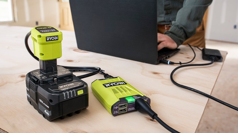 a person uses a 12v ryobi inverter to power up devices with a ryobi battery