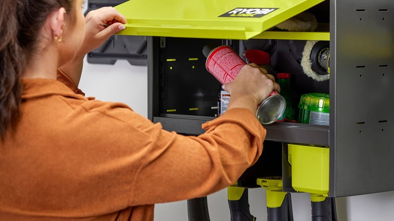 a woman stores DIY supplies in a Ryobi lockable tool cabinet