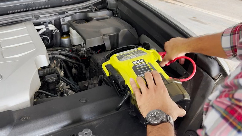 a person uses a Ryobi jump starter on their vehicle