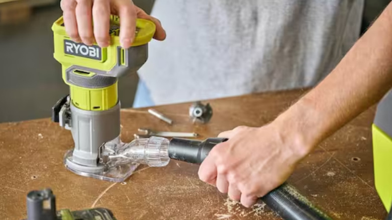 a person attaches a vacuum to a compact ryobi router