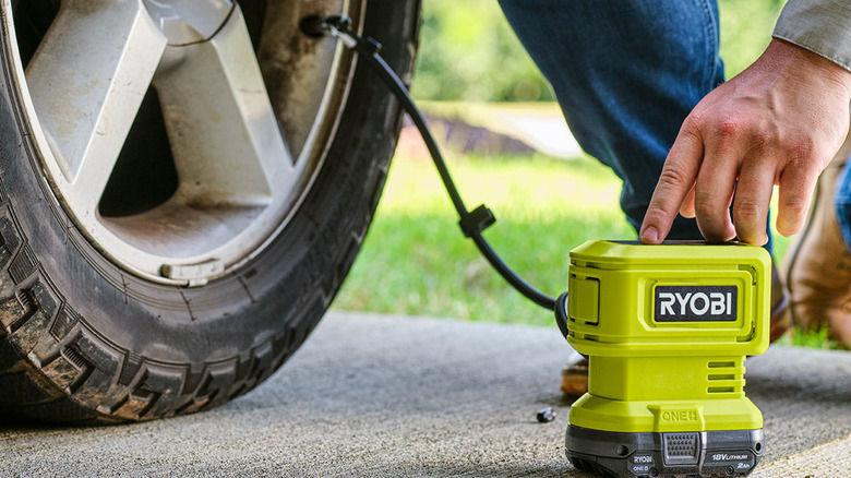 a person uses the ryobi 18v high pressure inflator to inflate a tire